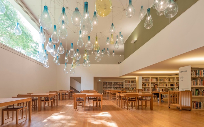 Library interior at Serralves with unique hanging light fixtures and wooden tables.