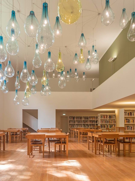 Library interior at Serralves with unique hanging light fixtures and wooden tables.