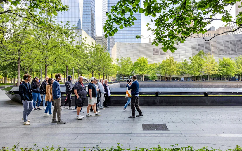 #Visitors at the 9/11 Memorial in New York City, with trees and skyscrapers in the background.