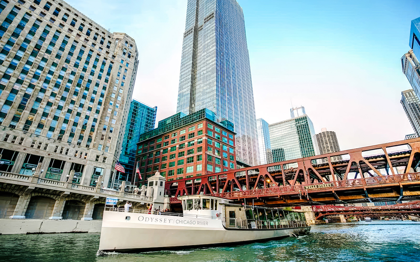 Cruise boat on Chicago River with city skyscrapers and bridge in view.
