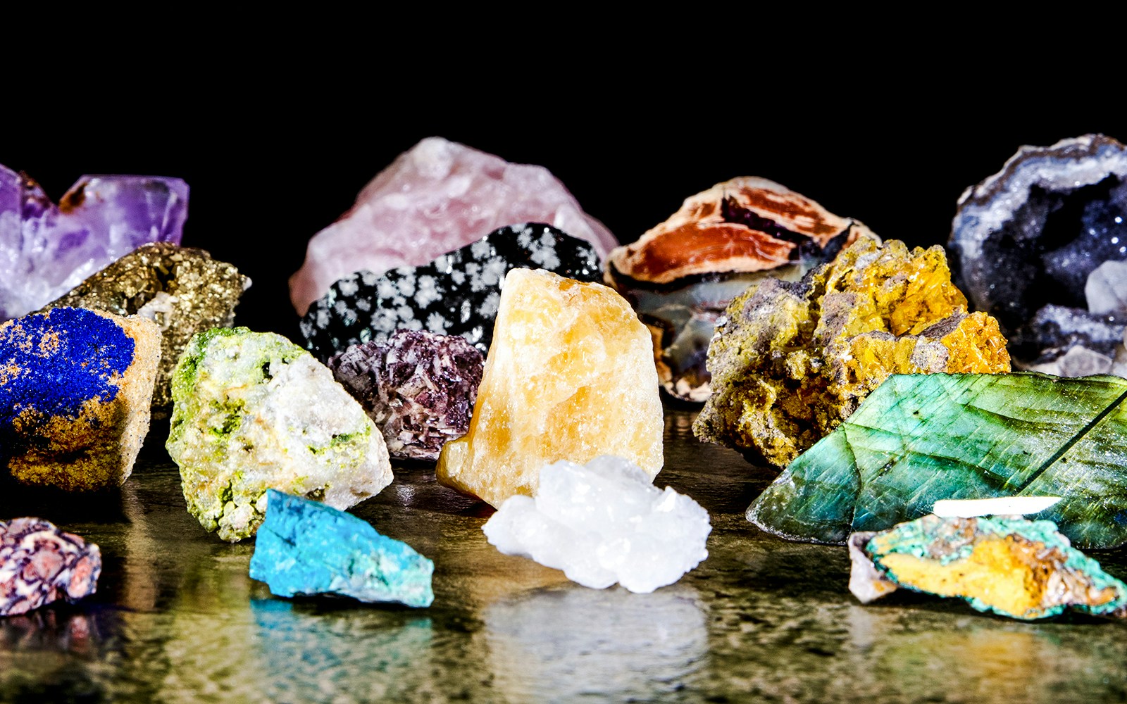 Various colorful minerals displayed on a reflective surface, associated with MIM Mineral.