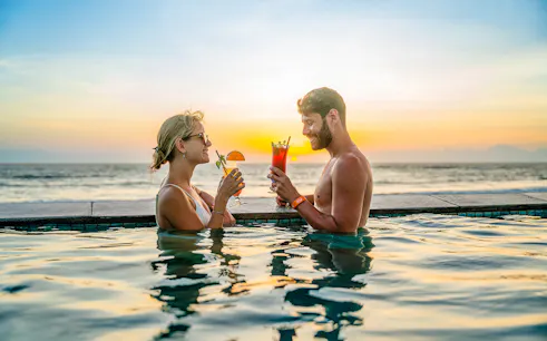 People enjoying drinks in the pool at Atlas Beach Club, Bali during sunset.
