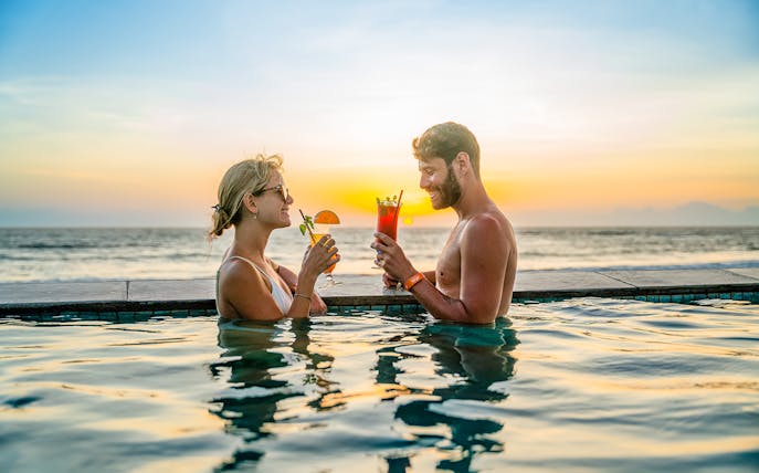 People enjoying drinks in the pool at Atlas Beach Club, Bali during sunset.