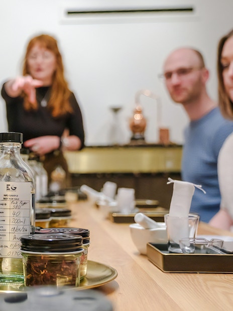 Participants at a gin making class in Edinburgh, focusing on bottles and ingredients on the table.