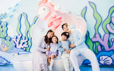 Family smiling in front of a colorful marine-themed backdrop at Ocean Park.