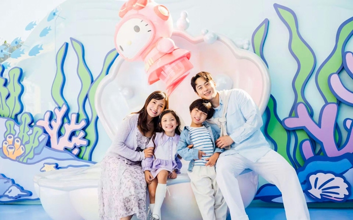Family smiling in front of a colorful marine-themed backdrop at Ocean Park.