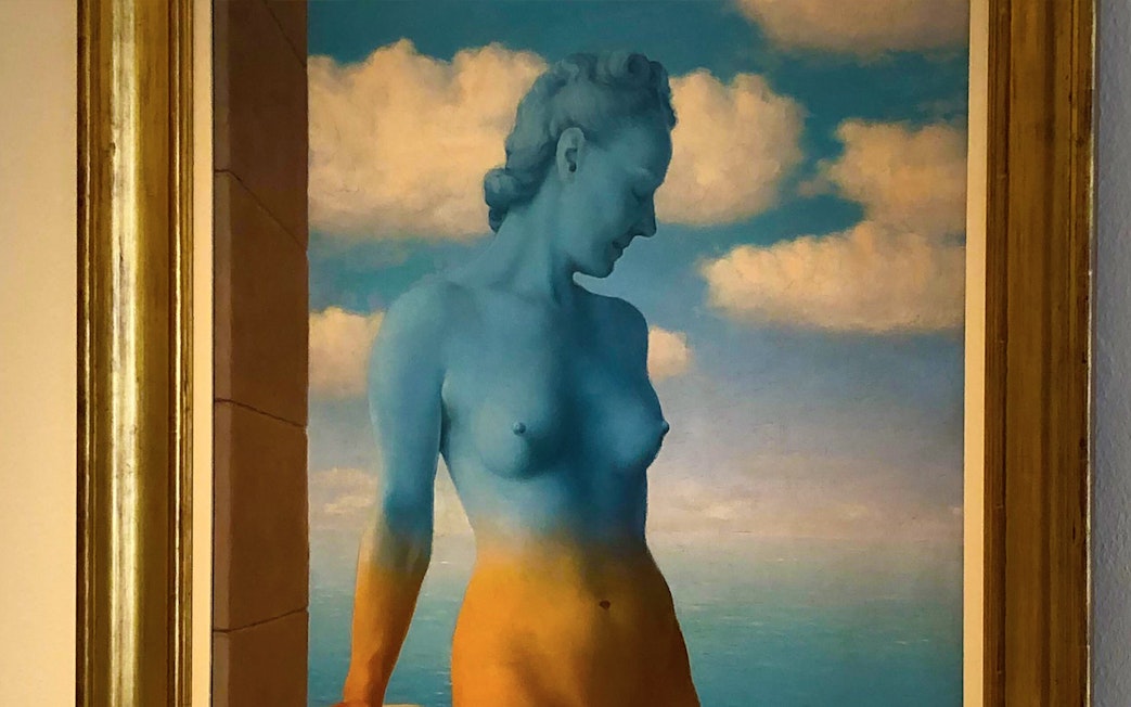 Surreal painting of a blue and orange figure against a cloudy sky at Peggy Guggenheim Collection.