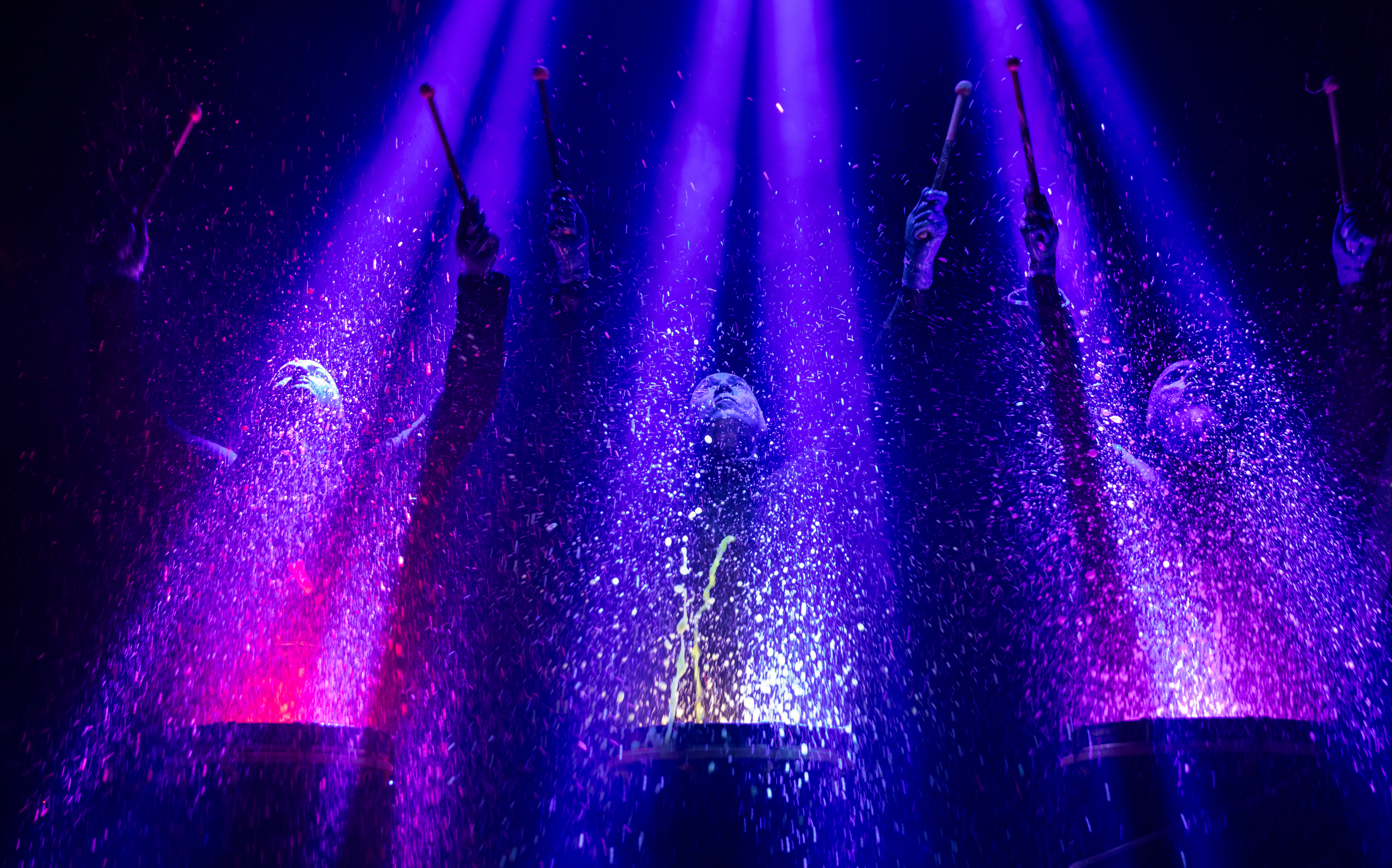 Blue Man Group performing with colorful lights and water effects in Orlando.