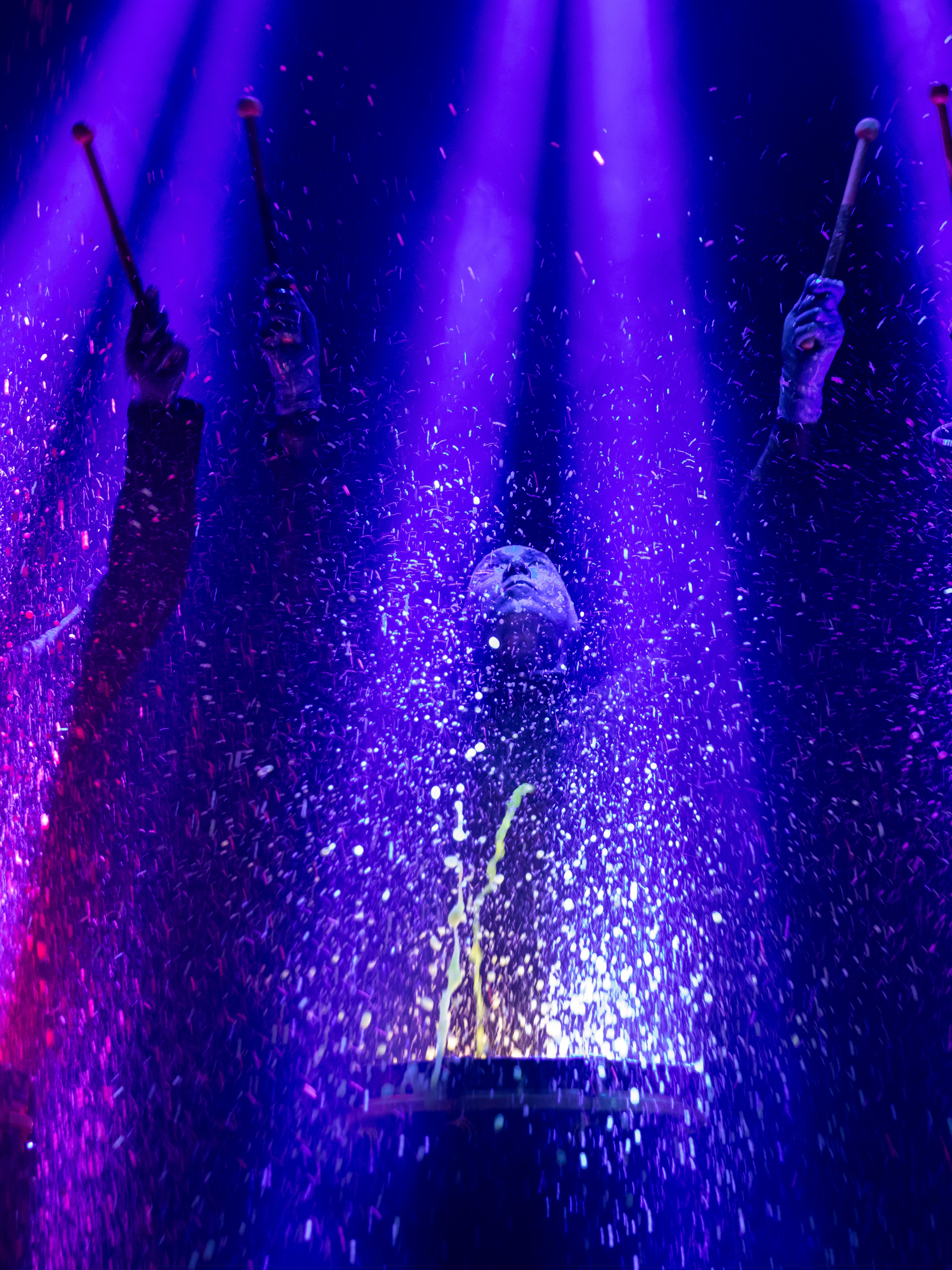 Blue Man Group performing with colorful lights and water effects in Orlando.