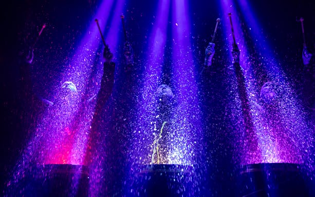 Blue Man Group performing with colorful lights and water effects in Orlando.