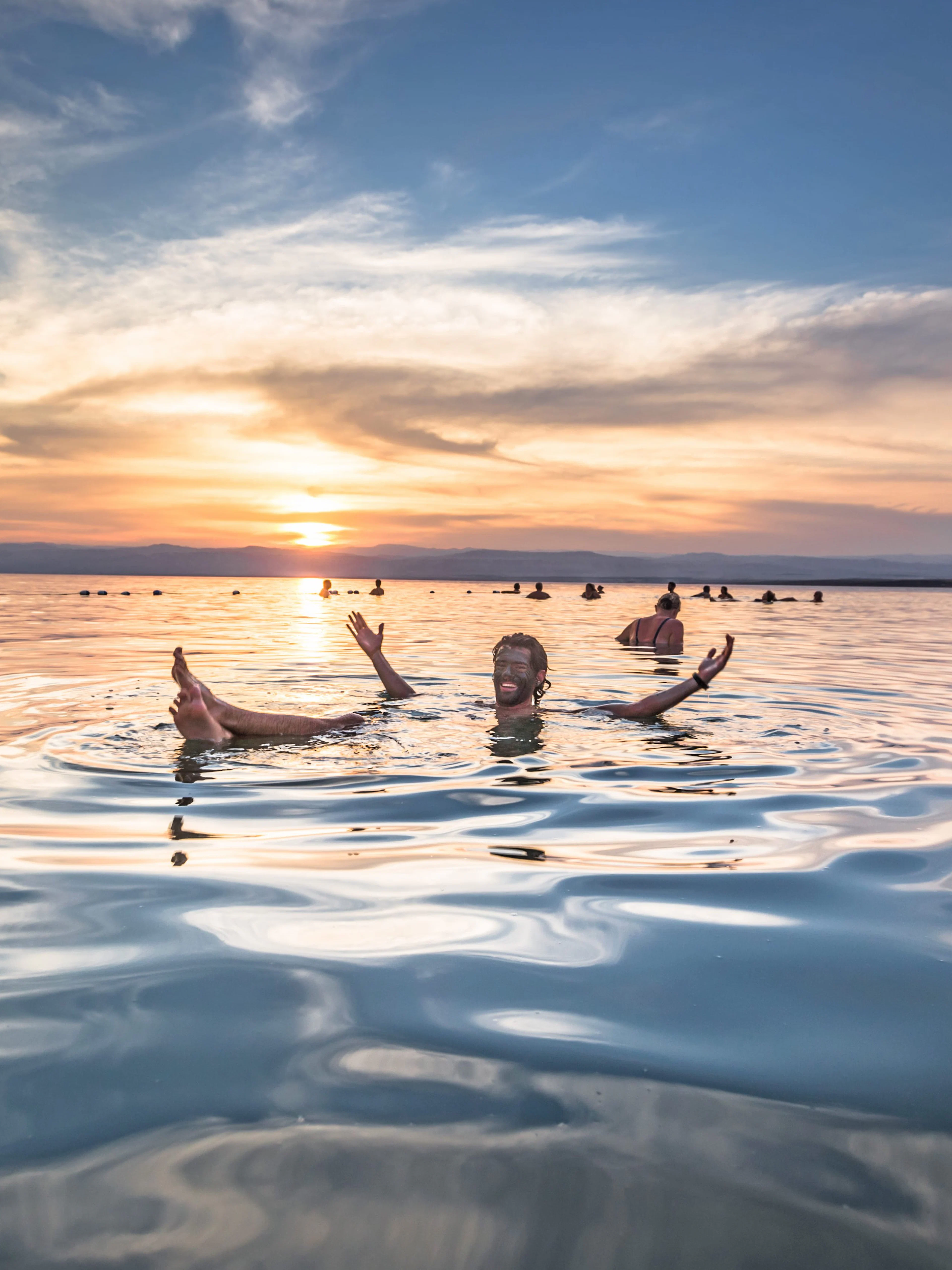 Floating man in Dead Sea at sunset, Jordan.