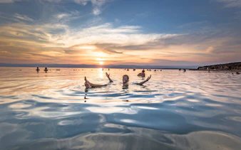 Floating man in Dead Sea at sunset, Jordan.