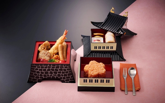 Traditional Japanese meal in bento boxes with tempura, rice, and side dishes.