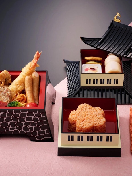 Traditional Japanese meal in bento boxes with tempura, rice, and side dishes.