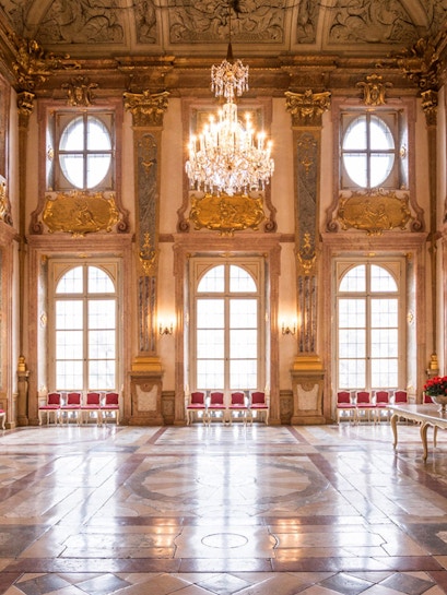 Mirabell Palace interior with ornate ceiling, chandelier, and large windows in Salzburg, Austria.