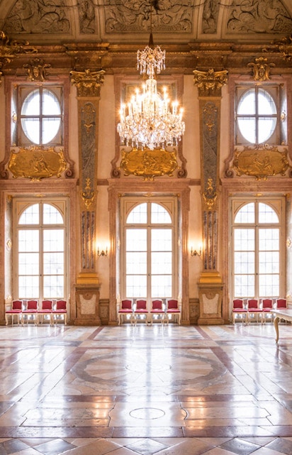 Mirabell Palace interior with ornate ceiling, chandelier, and large windows in Salzburg, Austria.
