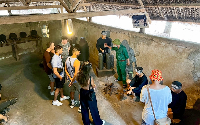 Tour group with guide learning about kitchen works during war at Cu Chi Tunnel, Vietnam.