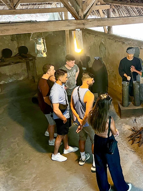 Tour group with guide learning about kitchen works during war at Cu Chi Tunnel, Vietnam.