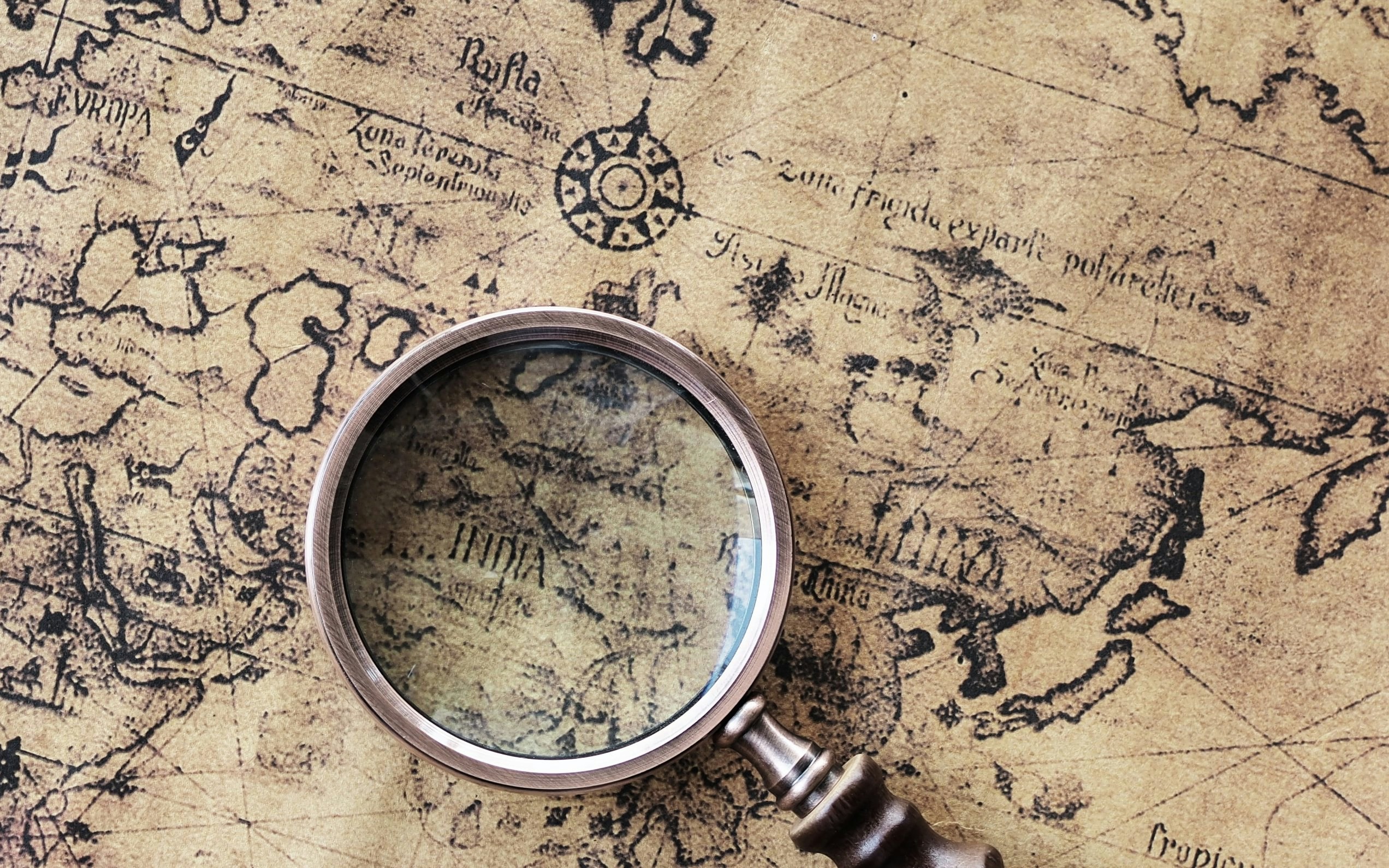 Magnifying glass on an old world map highlighting India.