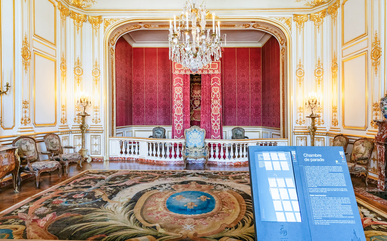 Chambord Castle interior with ornate red walls, chandelier, and decorative chairs.