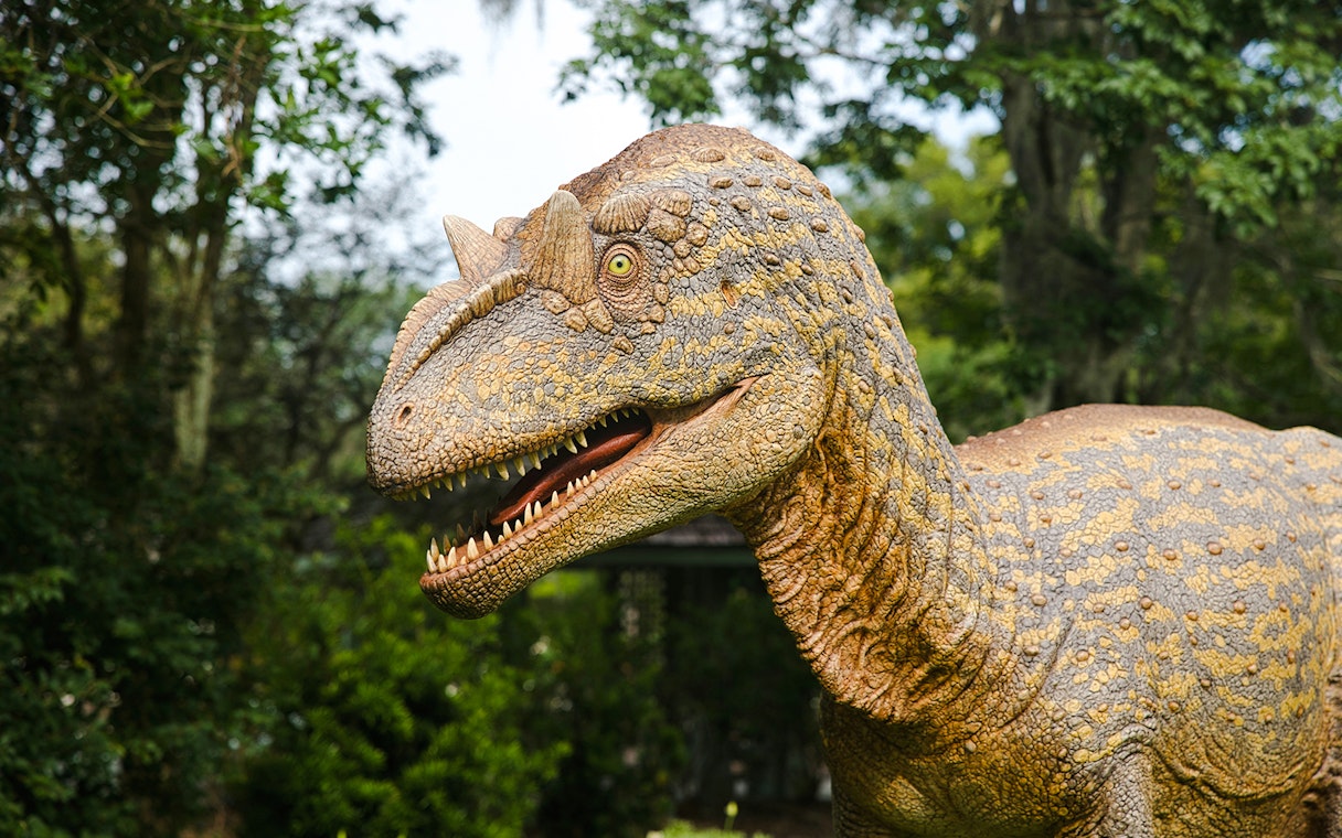 Realistic dinosaur model in a lush outdoor setting.
