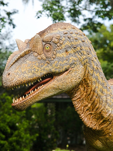 Realistic dinosaur model in a lush outdoor setting.