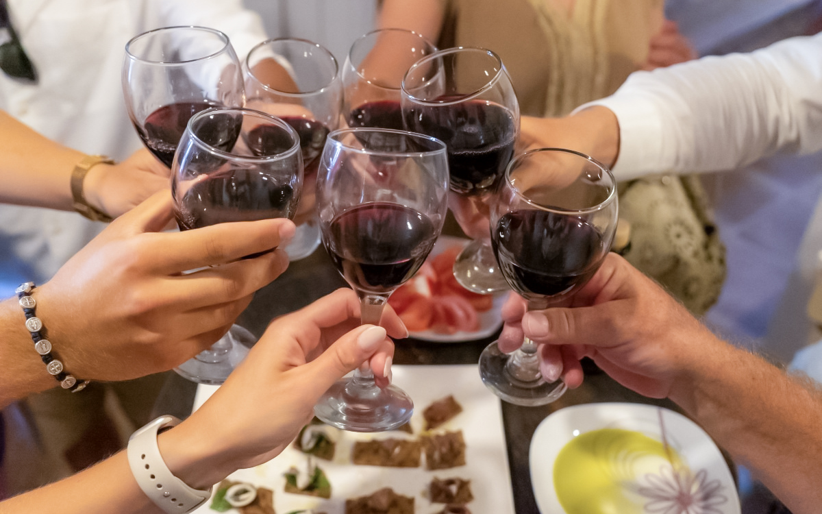 Wine glasses raised in a toast during a guided speedboat tour with food, oil, and wine tasting.