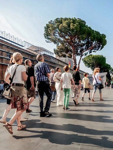 Visitors on a guided tour of Vatican Museums with St. Peter's Basilica in the background.