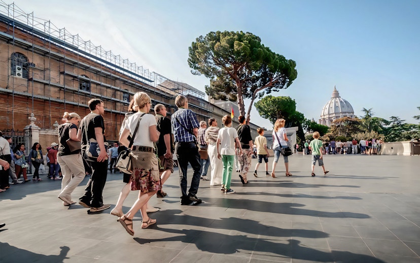 Visitors on a guided tour of Vatican Museums with St. Peter's Basilica in the background.