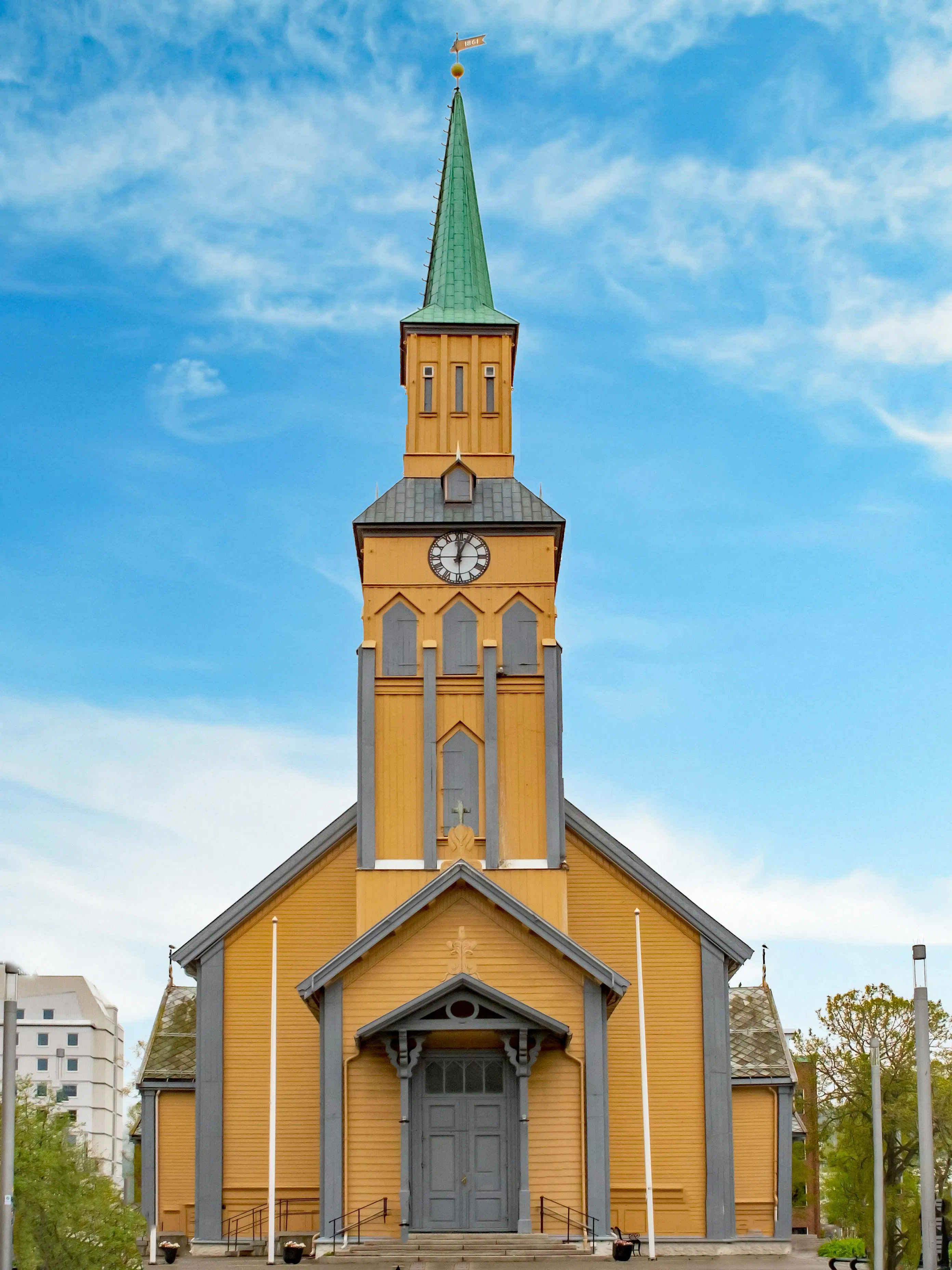 Tromsø Cathedral with its distinctive yellow wooden facade and green spire.
