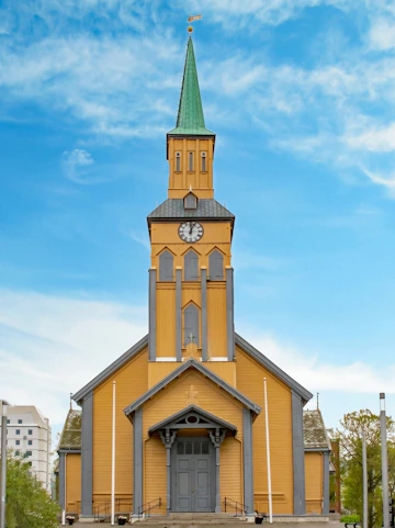 Tromsø Cathedral with its distinctive yellow wooden facade and green spire.