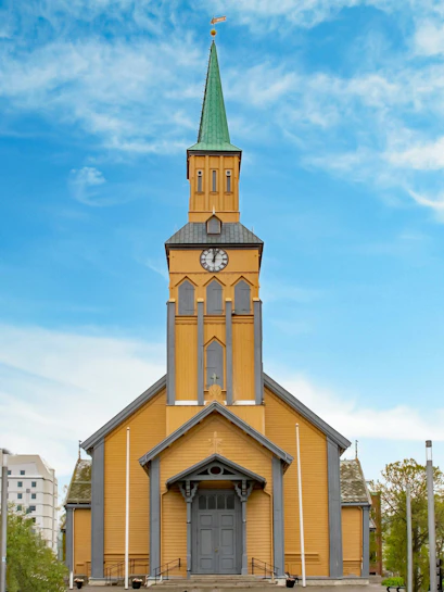 Tromsø Cathedral with its distinctive yellow wooden facade and green spire.