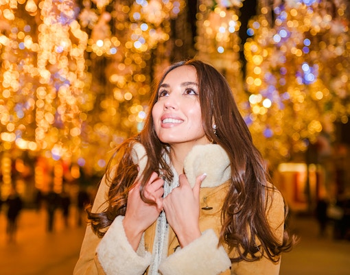 Woman enjoying festive city lights at night.