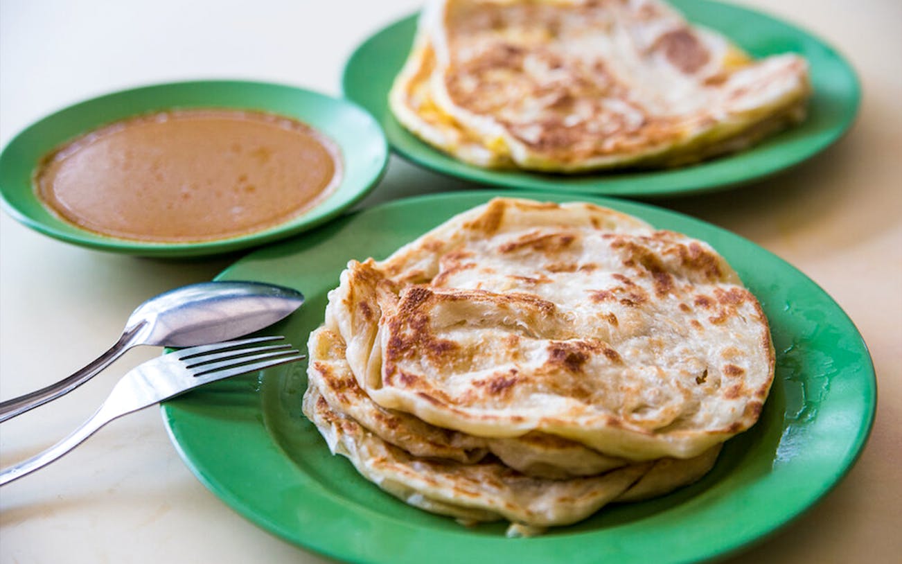 Roti prata with curry sauce on green plates, Singapore Chinatown food tour.