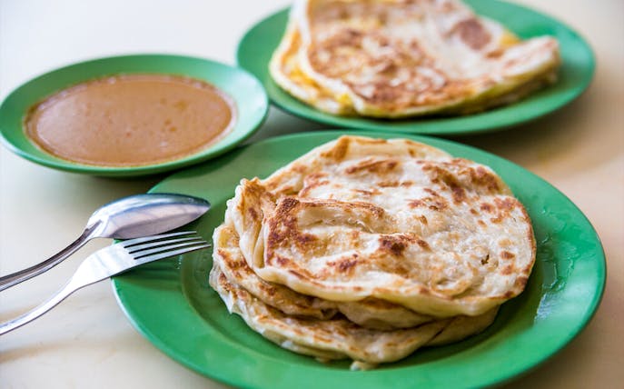 Roti prata with curry sauce on green plates, Singapore Chinatown food tour.