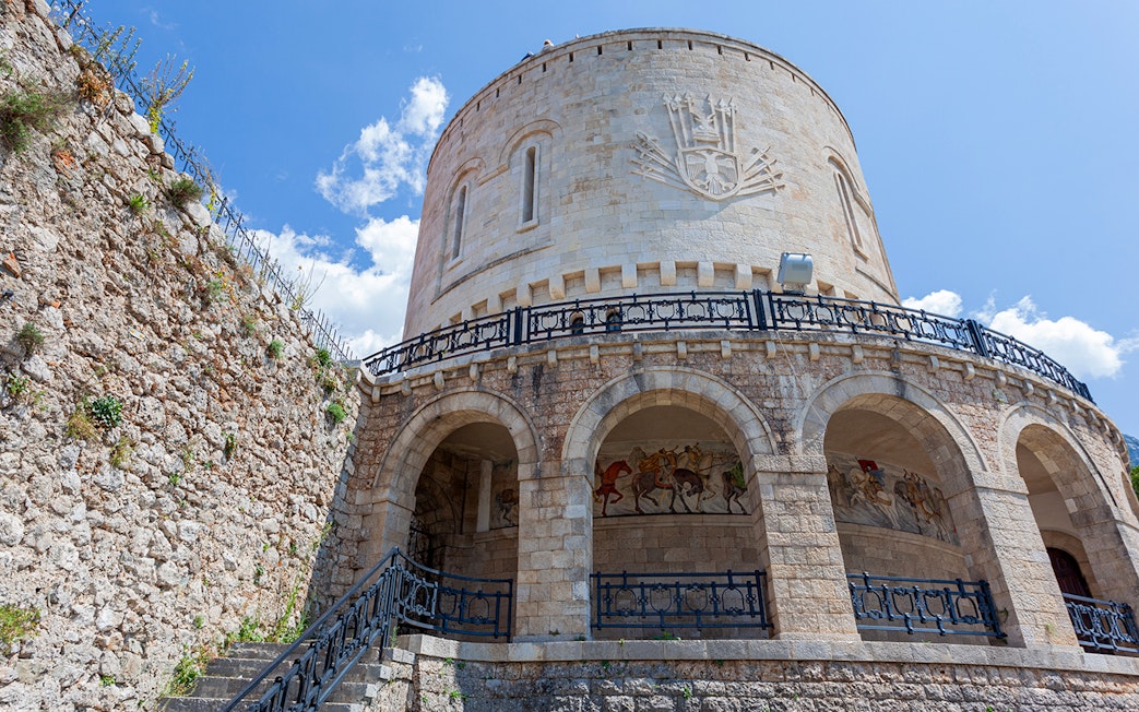 Kruje Fortress Museum stone tower with arches and mural, Albania.