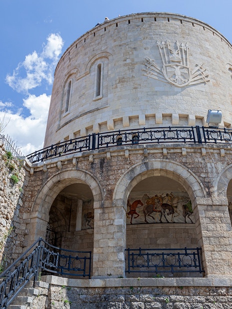 Kruje Fortress Museum stone tower with arches and mural, Albania.