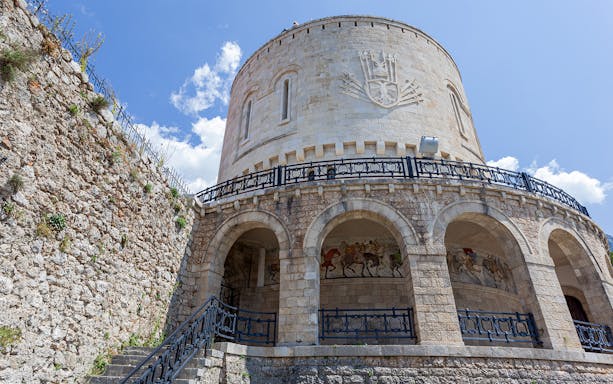 Kruje Fortress Museum stone tower with arches and mural, Albania.