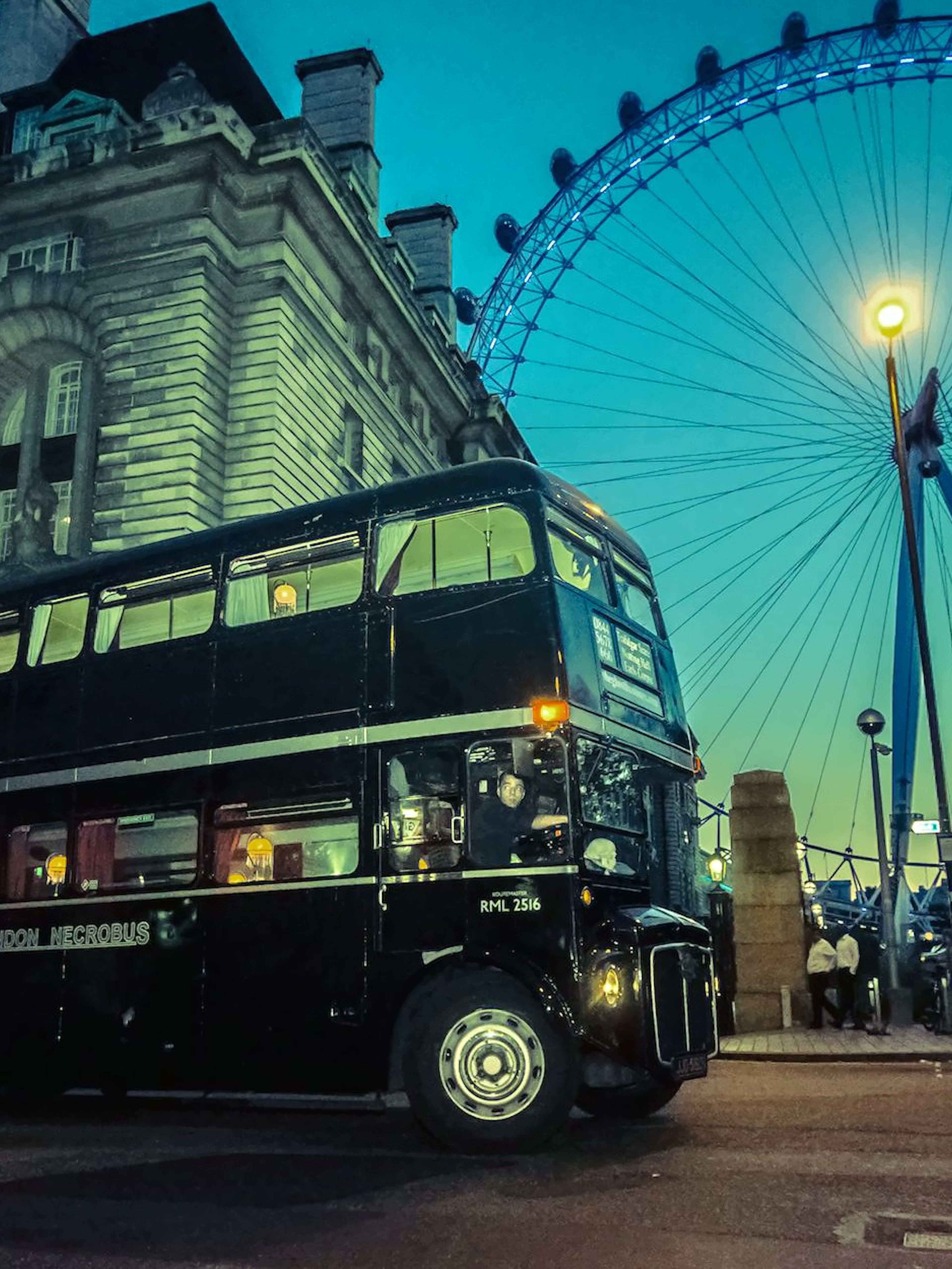 Vintage double-decker bus on London ghost tour near the London Eye at dusk.