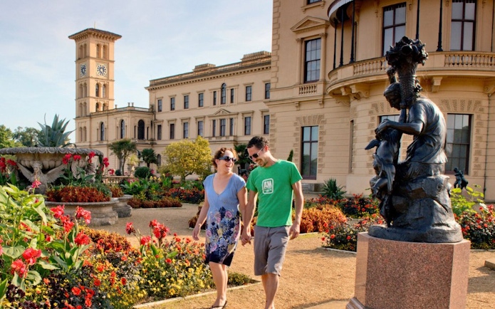 Couple walking in the gardens of Osborne House, Isle of Wight, with historic architecture in the background.