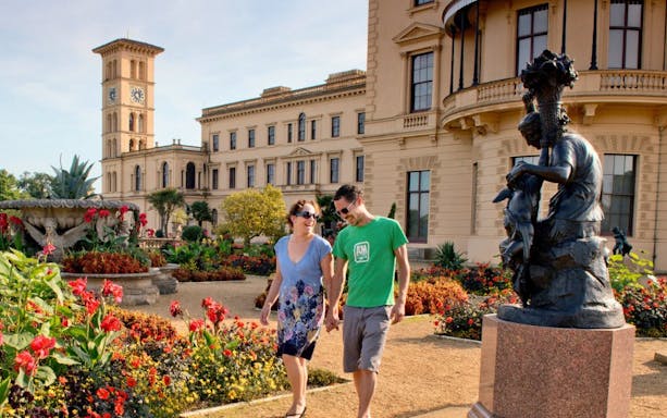 Couple walking in the gardens of Osborne House, Isle of Wight, with historic architecture in the background.