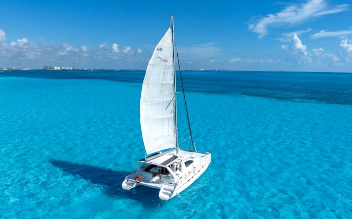 Catamaran sailing on clear blue waters near Isla Mujeres.