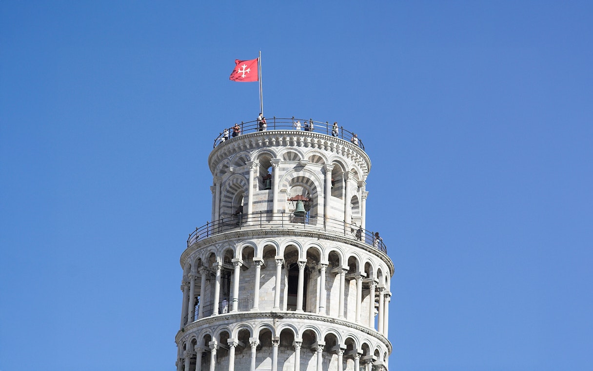 Tourists atop Leaning Tower of Pisa enjoying panoramic views.