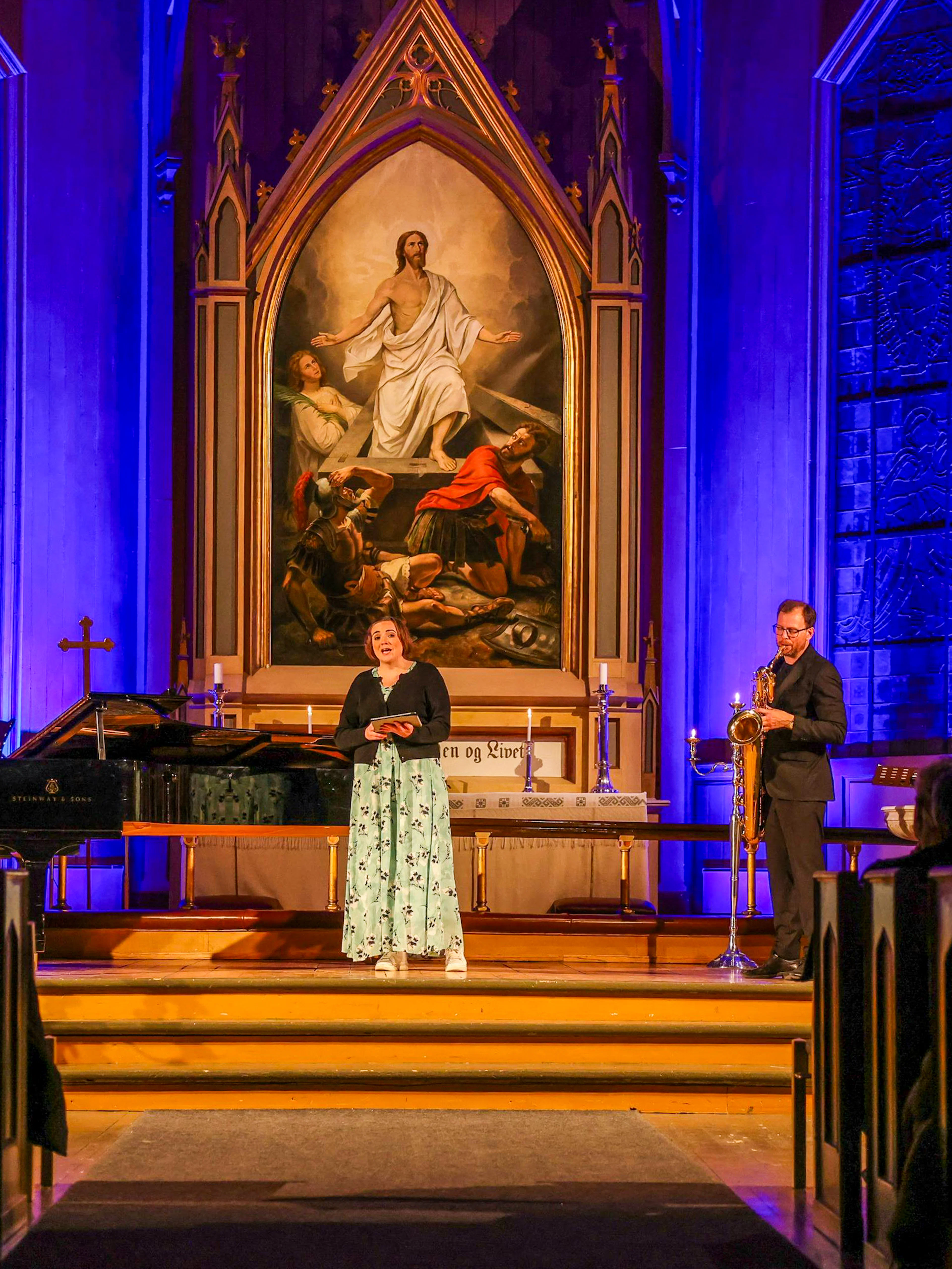 Performers at midnight concert in Tromsø Cathedral with illuminated altar backdrop.