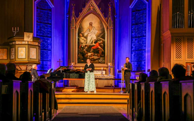 Performers at midnight concert in Tromsø Cathedral with illuminated altar backdrop.