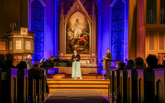 Performers at midnight concert in Tromsø Cathedral with illuminated altar backdrop.
