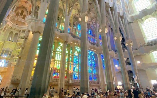 Sagrada Familia interior with colorful stained glass windows and visitors exploring.