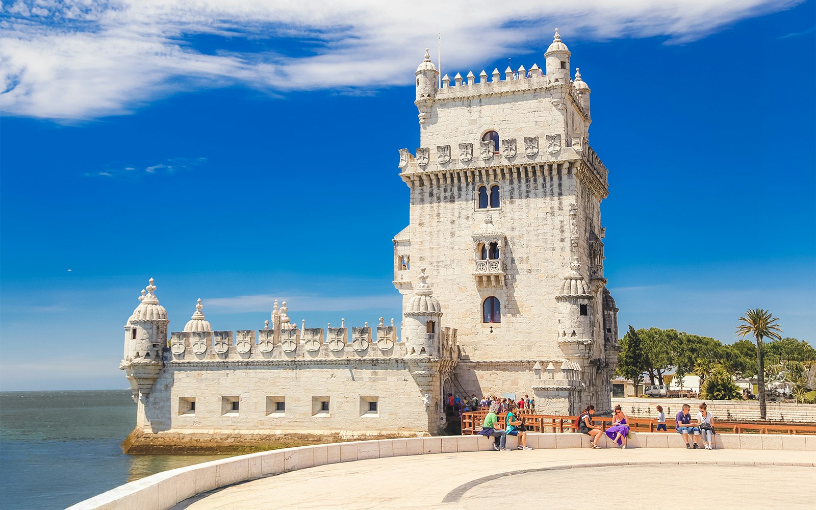 Visitors sitting near Belem Tower, Lisbon, enjoying the view.
