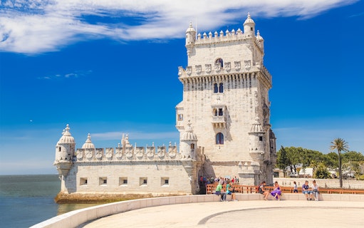 People sitting near Belem Tower in Lisbon, Portugal.
