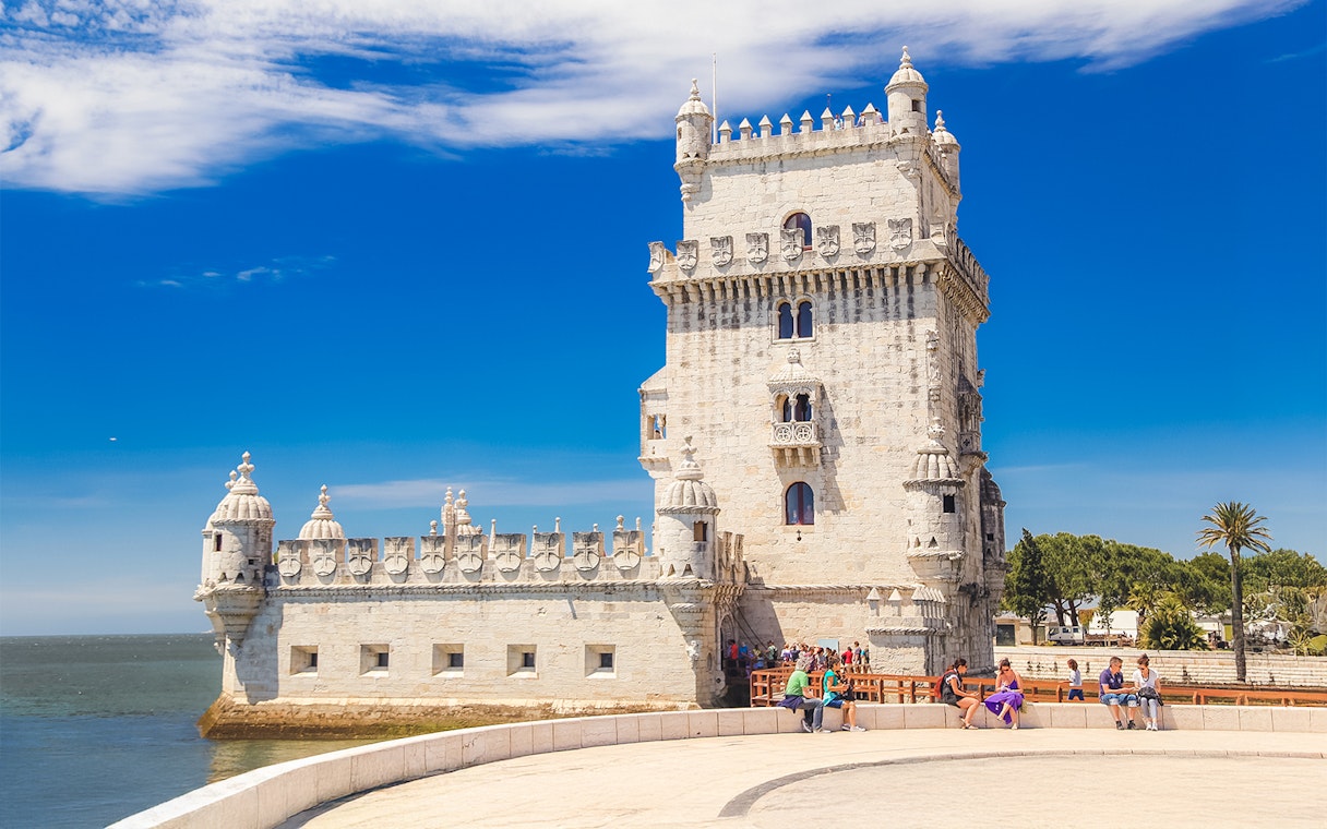 People sitting near Belem Tower in Lisbon, Portugal.